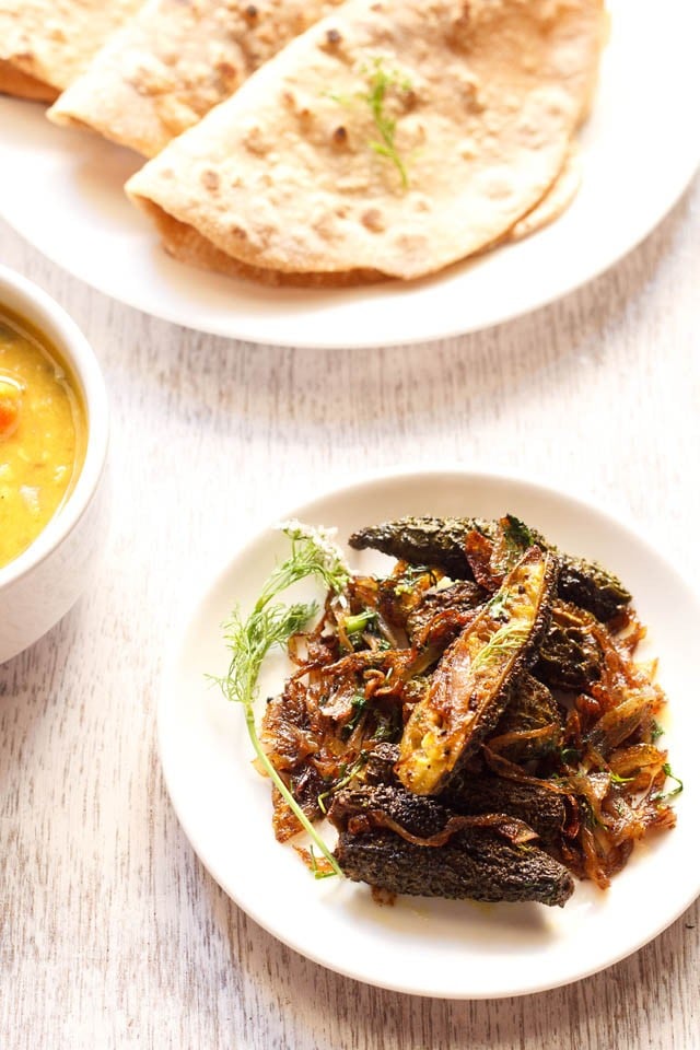 Punjabi bharwa karela served on a white plate with roti