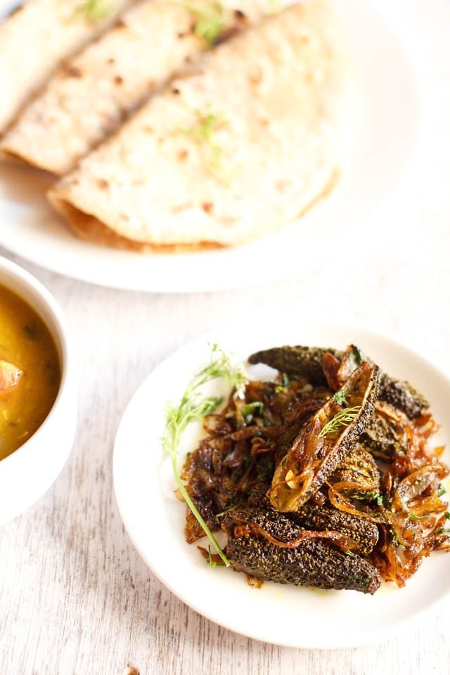 bharwa karela served on a white plate with roti.