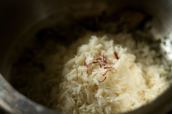 adding soaked rice and saffron strands