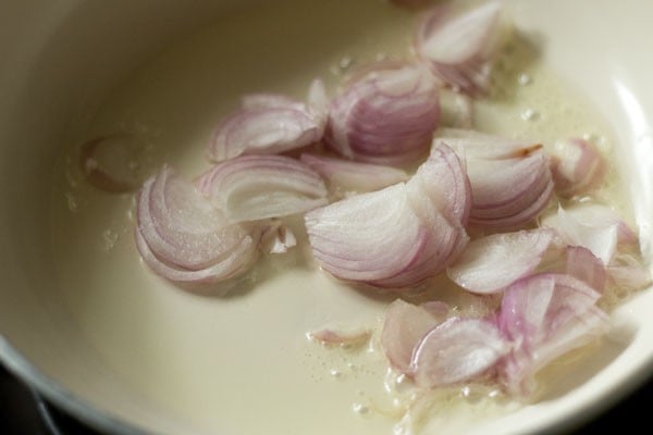 thinly sliced onions in hot oil in a white pan