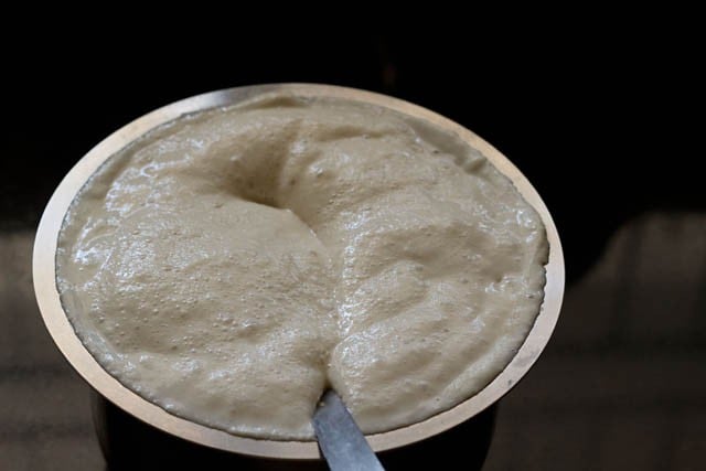 fermented dosa batter with a spoon in it. 