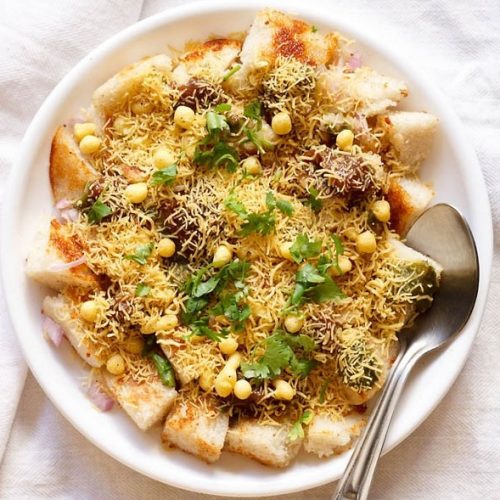 idli chaat in white plate with a spoon on white linen