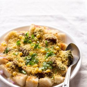 idli chaat in white plate with a spoon on white linen