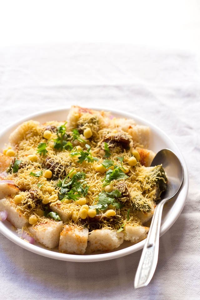 idli chaat in white plate with a spoon on white linen