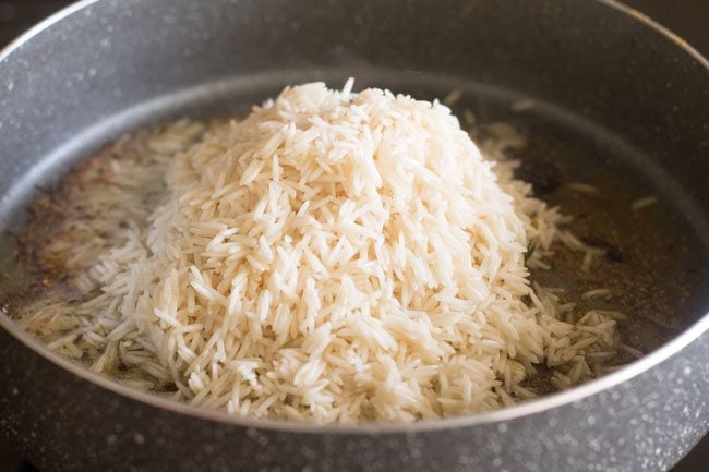 soaked and drained basmati rice added to pan with tempered spices