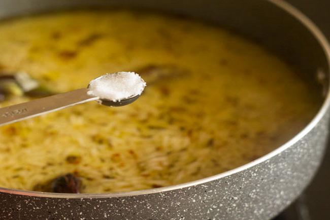 teaspoon of salt above pan with rice, spices and water