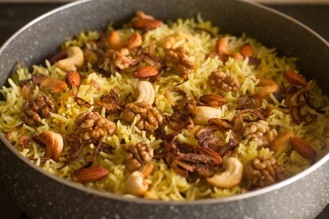 Kashmiri pulao topped with fried onions and nuts in the cooking pan