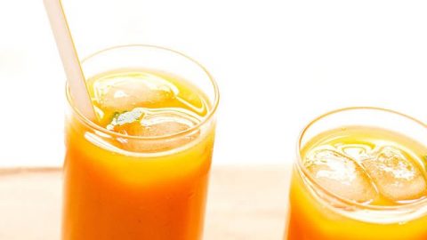 mango tea in two glasses with ice cubes and a straw in one glass
