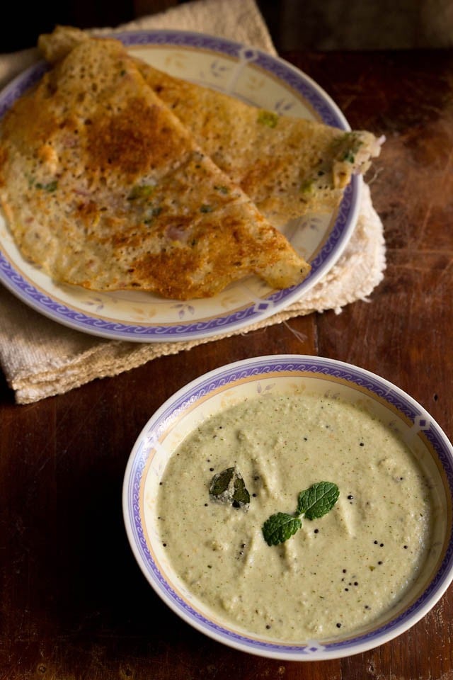pudina pachadi served in a bowl with rava dosa on a plate.