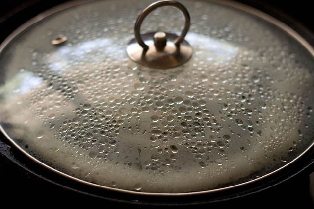 cooking dosa on covered tawa. 