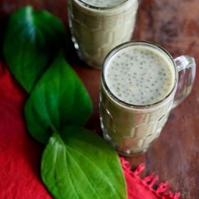 paan shots in two glasses with betel leaves placed at the side.