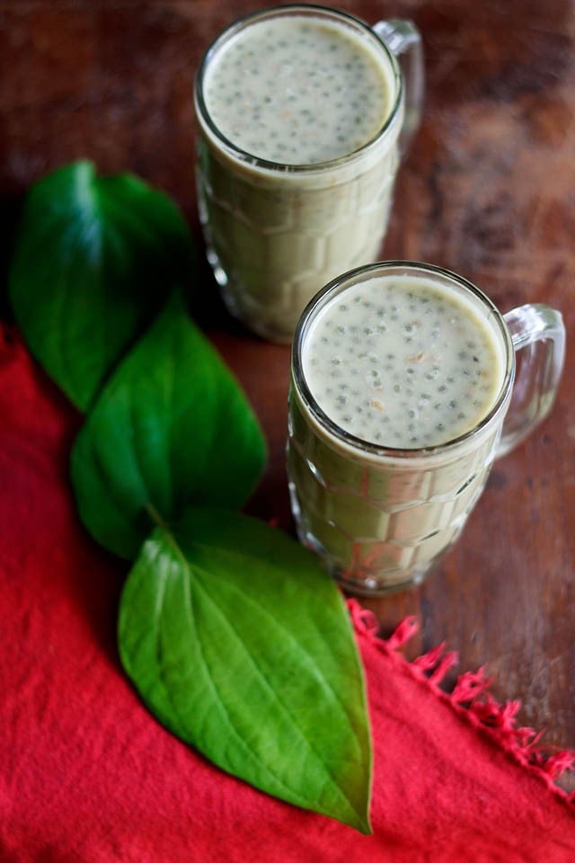 paan shots in two glasses with betel leaves placed at the side.