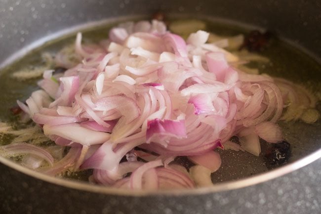 adding onions to pan for palak biryani