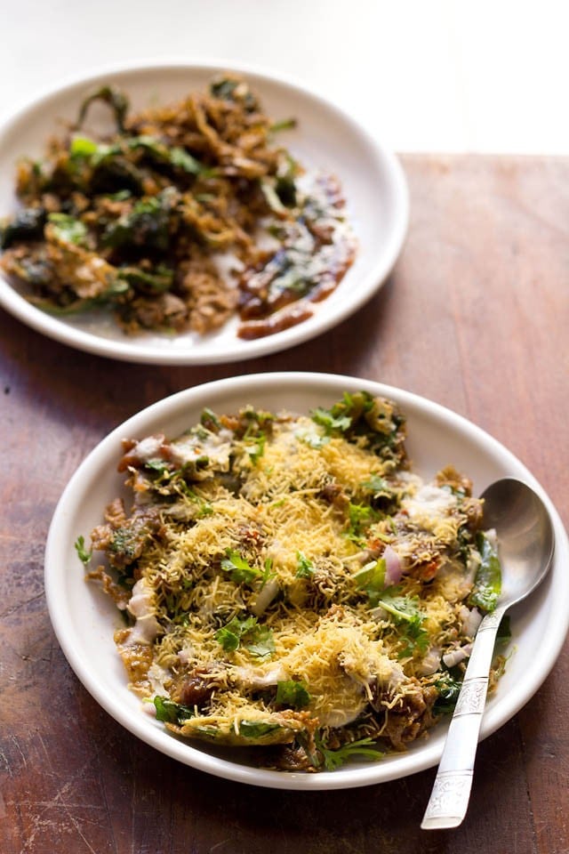 palak patta chaat served on white plates with a spoon kept on right side on one of the plates. 