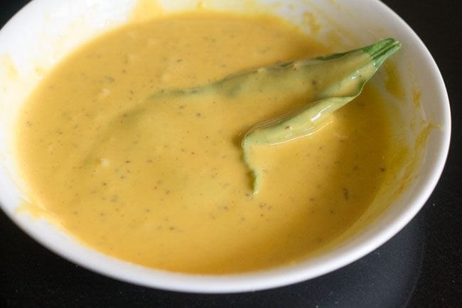 dipping each spinach leaf in the prepared batter. 