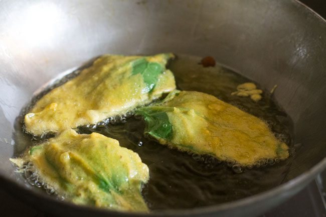frying batter coated spinach leaves in hot oil. 