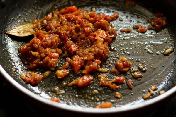 mixing spice powders with the softened tomatoes and onions in the pan