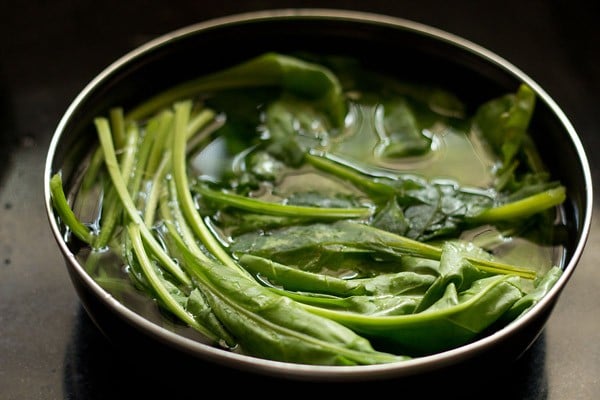 spinach being blanched in hot water to make palak paneer recipe