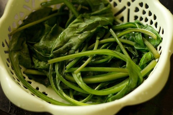straining palak leaves in a colander