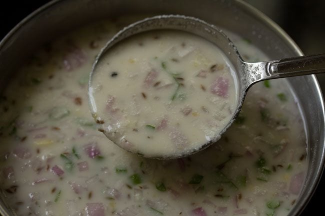 mixing the rava dosa batter with a ladle.