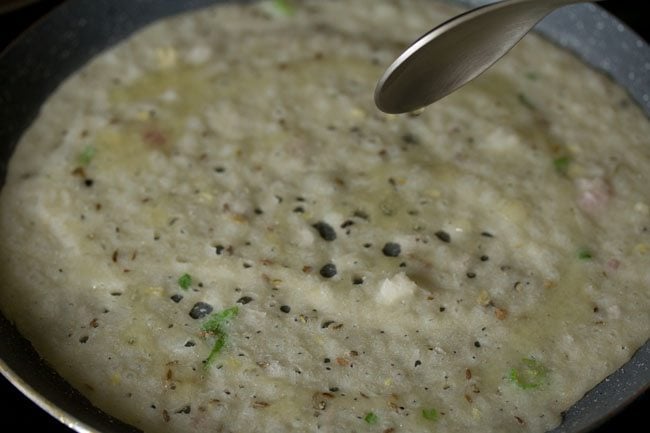 drizzling oil on top and sides of the rava dosa