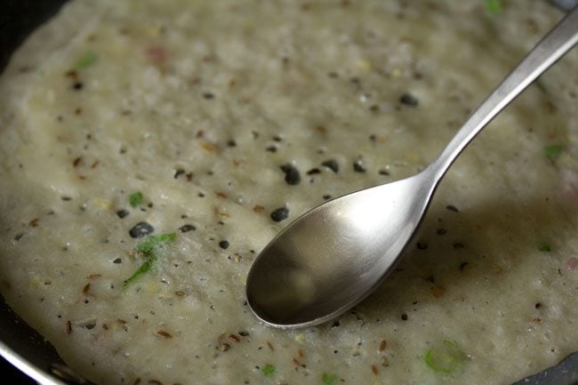 spreading oil on the suji ka dosa with a spoon