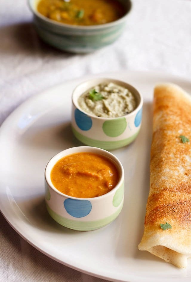 red chutney served in a bowl with dosa and coconut chutney 