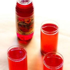 rooh afza sharbat in three glasses with a bottle of rooh afza syrup