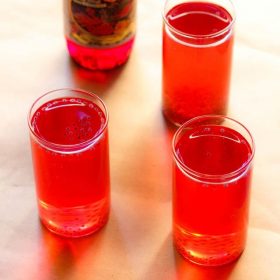 rooh afza sharbat in three glasses with a bottle of rooh afza syrup