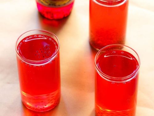 rooh afza sharbat in three glasses with a bottle of rooh afza syrup