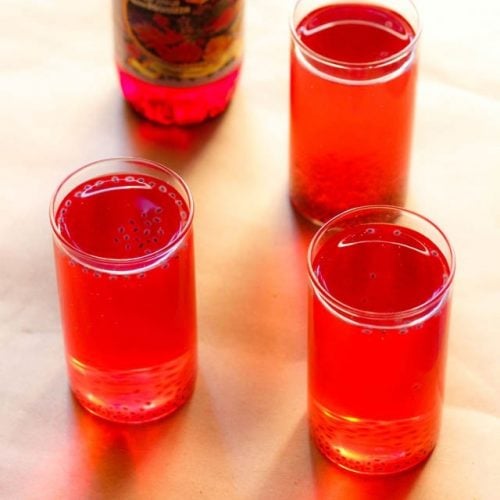 rooh afza sharbat in three glasses with a bottle of rooh afza syrup