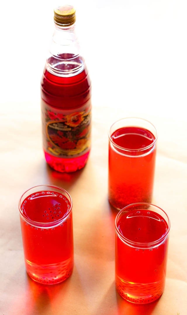 rooh afza sharbat in three glasses with a bottle of rooh afza syrup