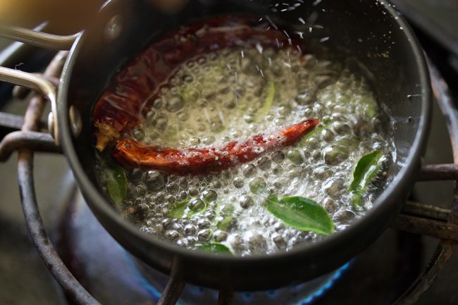 adding dried red chilies, curry leaves and asafoetida in hot oil for tempering of udupi sambar 