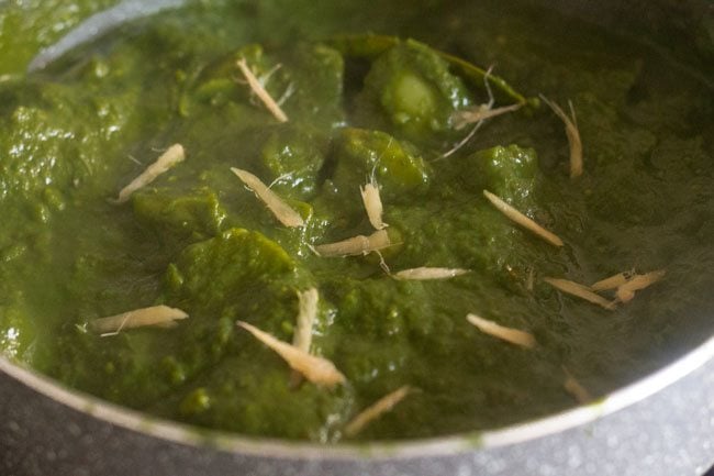 ginger julienne or thin ginger sticks on aloo palak gravy