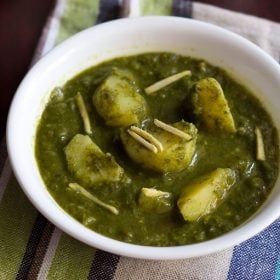 aloo palak garnished with ginger julienne in a white bowl on a blue green white cotton napkin