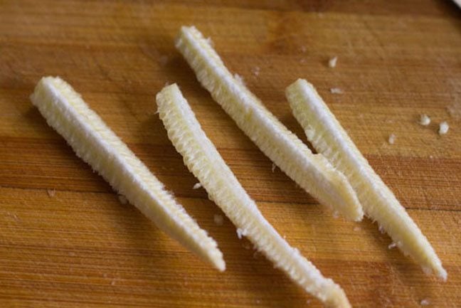 slicing each baby corn vertically into 4 pieces 