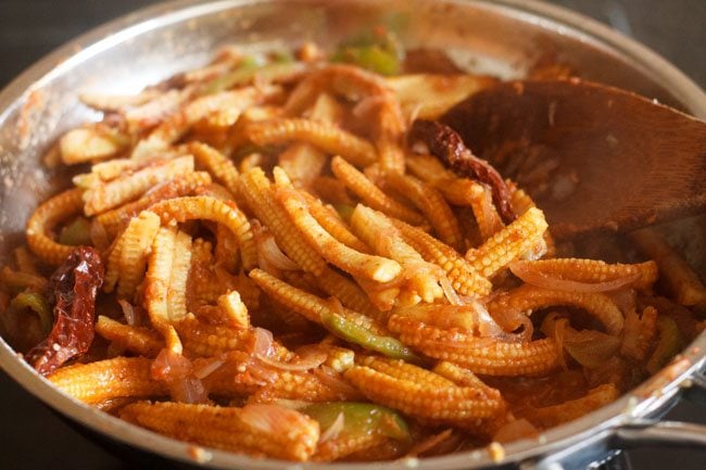 stirring well the baby corn jalfrezi mixture in pan