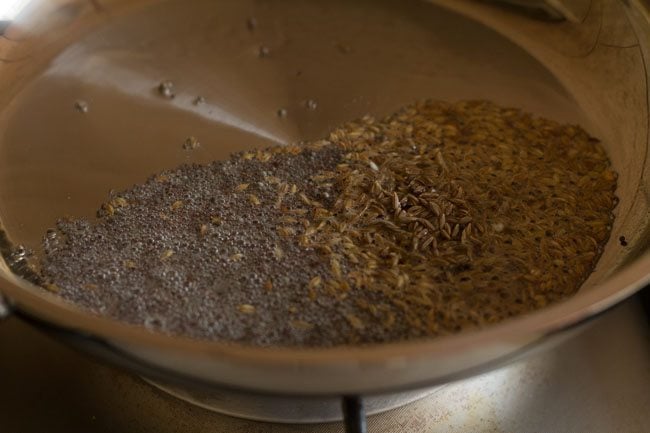 sautéing cumin seeds in hot oil in pan