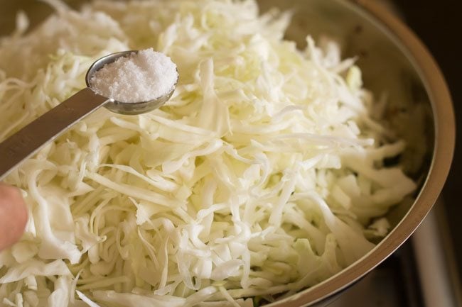 adding shredded cabbage and salt in pan to make cabbage thoran recipe