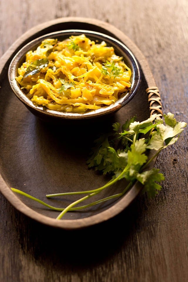 cabbage thoran served in a bowl with fresh coriander sprigs on the side 