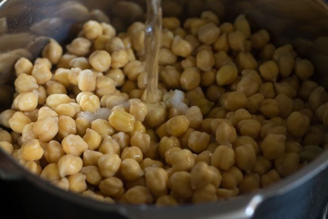 chickpeas, salt and water being added in a pressure cooker