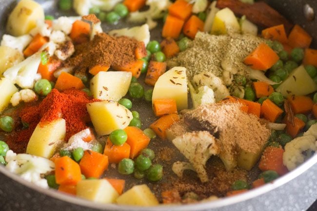 adding fennel powder, ginger powder, red chili powder, garam masala powder, asafoetida and grated nutmeg to the vegetables in the pan