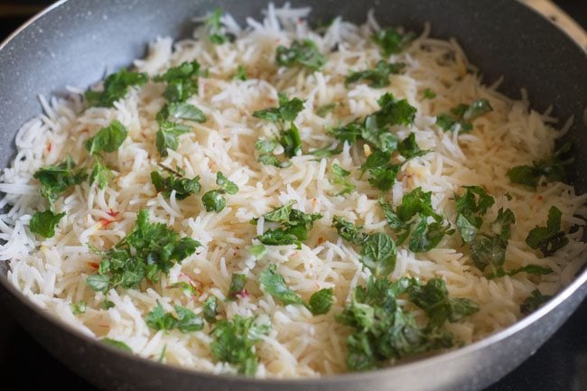 adding half the dissolved saffron on top of the rice in the pan