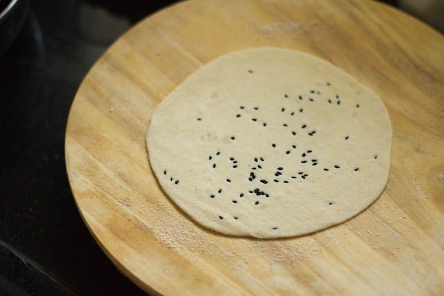 sprinkling nigella seeds on small dough balls and rolling into kulcha