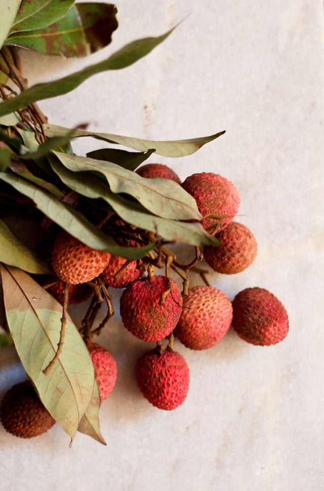 fresh lychee fruit with leaves on a marble table