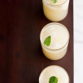 litchi juice (lychee juice) garnished with mint leaves and served in three glasses in a straight line