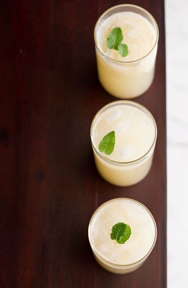 litchi juice (lychee juice) garnished with mint leaves and served in three glasses in a straight line