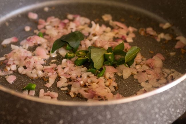 adding curry leaves and chopped green chili to the pan 