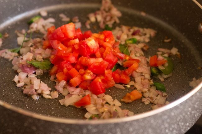 adding chopped tomato to the pan