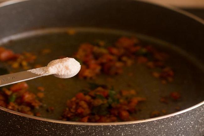 adding asafoetida and salt to the onion-tomato mixture in the pan